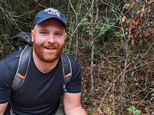 Man with rucksack in forest wearing and baseball cap